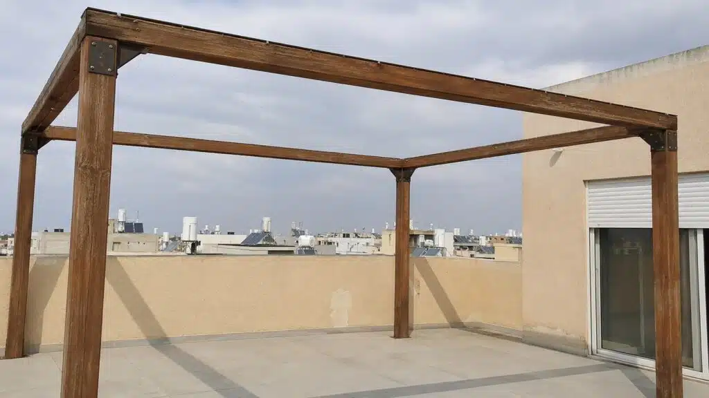 רשת מונופיל שקופה מתוחה על פרגולת עץ במרפסת גג של פנטהאוז, הנוף והשמיים נראים דרכה